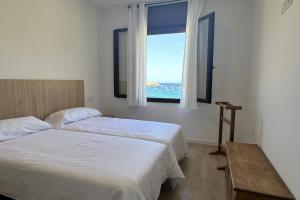 a bedroom with two beds and a window with the ocean at LETS HOLIDAYS Wake Up by the Sea in Victoria apartment 2 in Tossa de Mar