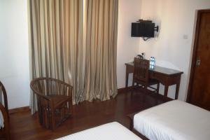 a room with a bed and a desk and a television at Daffodil's Hotel in Nuwara Eliya
