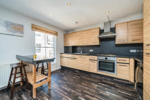 a kitchen with wooden cabinets and a table and a stove at ELGIN MEWS NORTH beside Maida Vale tube and parking LONG TERM BOOKINGS in London