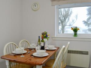 - une table en bois avec des chaises et des bouteilles de vin dans l'établissement Cotters Cottage - Uk10922, à Whithorn