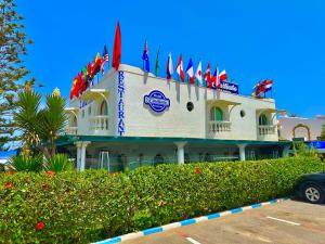 a building with a bunch of flags on top of it at Hotel L'Initiale in Oualidia
