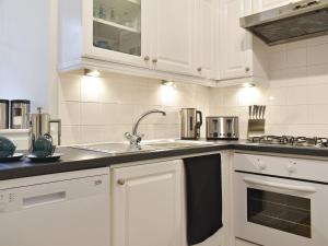 a kitchen with white cabinets and a sink at West Lodge in Banchory