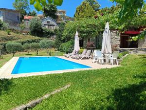 a swimming pool in a yard with umbrellas at Quinta do Pontido in Vieira do Minho