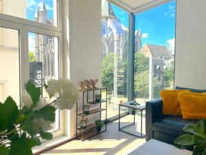 a living room with a blue couch and large windows at Historic Centre Apartment - Ghent Belfry & St Nicholas Church View in Ghent