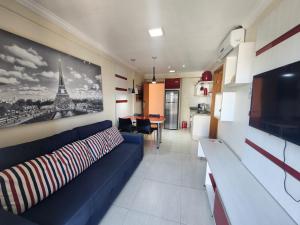 a living room with a blue couch and a picture of the eiffel tower at Apartamento Giardino Rio Quente in Rio Quente