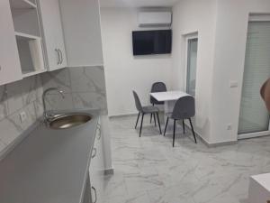a kitchen with a sink and a table with chairs at Apartman Centar Visegrad in Višegrad