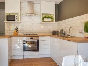 a kitchen with white cabinets and an oven at River Lodge Annexe in Rhondda +10 photos