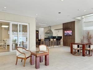 a lobby with a table and chairs and a kitchen at AC - Piscina - 1 Suite com banheiro - 200m do mar in Guarujá