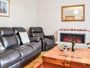 ein Wohnzimmer mit einer Ledercouch und einem Tisch in der Unterkunft High Threave Cottage in Kirkcowan