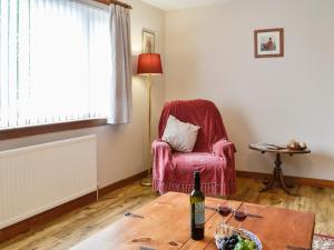 ein Wohnzimmer mit einem Sessel und einer Flasche Wein in der Unterkunft High Threave Cottage in Kirkcowan