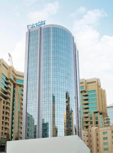 um edifício de vidro alto com uma placa em cima em Vita Tower em Manama