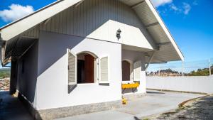 mały biały budynek z dużym dachem w obiekcie Casa com lareira, Wi-Fi e varanda com vista w mieście Campos do Jordão