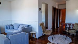 salon z niebieską kanapą i stołem w obiekcie Casa com lareira, Wi-Fi e varanda com vista w mieście Campos do Jordão