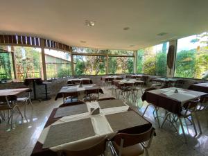 a restaurant with tables and chairs and large windows at Hotel Fazenda Tucano in Capim Branco