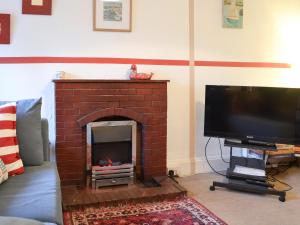 a living room with a brick fireplace with a flat screen tv at Gaerwen in Criccieth