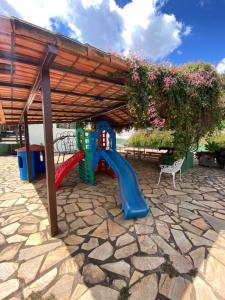 a playground with a slide and a bench under a roof at Hotel Fazenda Tucano in Capim Branco