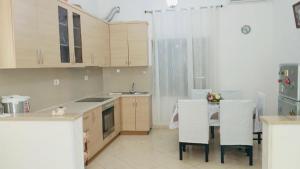 a kitchen with white cabinets and a table and chairs at Brois Home in Orikum