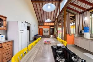 a kitchen with a long table and yellow chairs at Casa no Centro de Bonito no condomínio Eco Bonito in Bonito