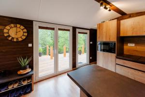 a kitchen with sliding glass doors and a clock on the wall at Chatka v Oravskom Zátiší in Jasenica