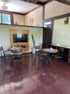 a dining room with two tables and chairs and a flat screen tv at Casa da Tartaruga Búzios in Búzios +78 photos