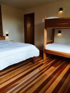 a bedroom with two bunk beds and wooden floors at Villa Mantiqueira - Studio II - Com lareira e área verde in Campos do Jordão