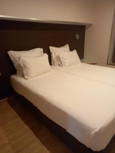 a large bed with white sheets and pillows at Hotel Bocage in Setúbal