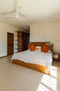 a bedroom with a large white bed with orange pillows at Charlotte Villa in Takamaka