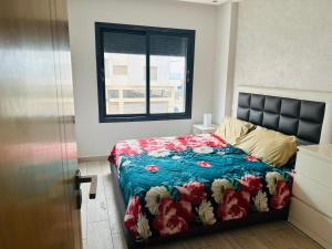 a bedroom with a bed with a blue comforter and a window at Appartement vu sur mer in Pont Blondin