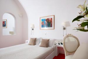 a white bedroom with a bed and a mirror at Whitedeck Santorini in Imerovigli