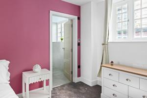 a bedroom with purple walls and a white bed and a mirror at Luxury Apartment in Nottinghams Best Location in Nottingham