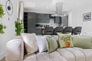 a living room with a couch with pillows and a kitchen at Luxury Apartment in Nottinghams Best Location in Nottingham