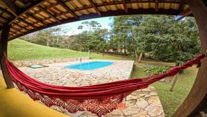 a hammock in a house with a swimming pool at Suíte em São Francisco Xavier ao Redor da Natureza in São Francisco Xavier