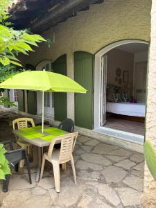 a table with a green umbrella on a patio at Chambre Bohème chic avec jacuzzi in Liouc