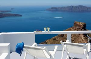 Duas cadeiras brancas sentadas numa varanda com vista para o oceano em Whitedeck Santorini em Imerovigli