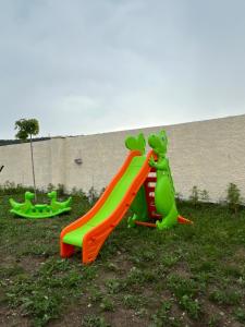 two childrens play equipment in the grass with a slide at hOlarooms N1 in Sachure