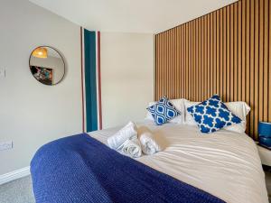 a bed with blue and white pillows on it at Mulberry House, Dowlais in Merthyr Tydfil