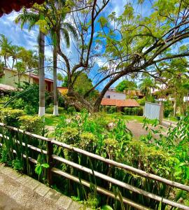 a fence in front of a park with trees and flowers at Pousada Praia da Pipa in Pipa