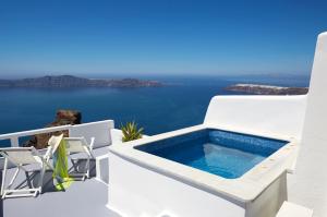 uma piscina ao lado de uma casa com o oceano em Whitedeck Santorini em Imerovigli