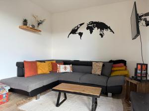 a living room with a gray couch and a world map on the wall at la maison de la mer in Port-Bail-sur-Mer