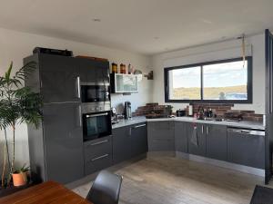a kitchen with gray cabinets and a large window at la maison de la mer in Port-Bail-sur-Mer