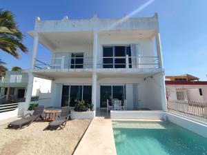 a white house with a swimming pool and two chairs at Casa junto a la playa en Chelem in Chelem