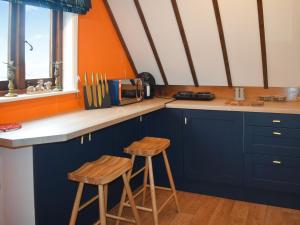 a kitchen with blue cabinets and two wooden stools at Kingfisher Granary in Ashburnham