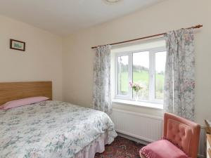 a bedroom with a bed and a window at Bank Top Cottage in Hathersage