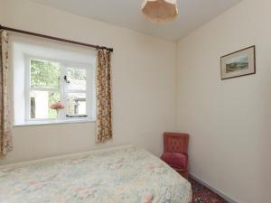 a bedroom with a bed and a window and a chair at Bank Top Cottage in Hathersage +5 photos