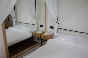 two beds in a small room with white sheets at Cozy Hideaway Your Urban Escape in Craiova