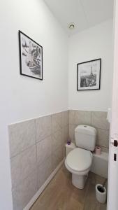 ein Badezimmer mit WC und zwei Bildern an der Wand in der Unterkunft Le Miel d'Opale - Ferry, Shuttle and Beach in Calais