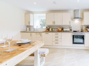 a kitchen with white cabinets and a wooden table at Ty Draenog - Uk31653 in New Quay +11 photos