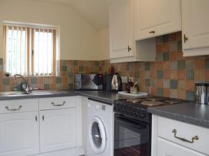 a kitchen with white cabinets and a dishwasher at Y Bwthyn-Uk31367 in Tregynon