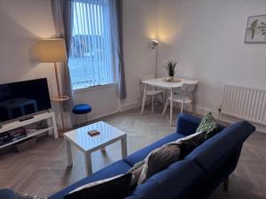 a living room with a blue couch and a table at Balloch But & Ben in Balloch