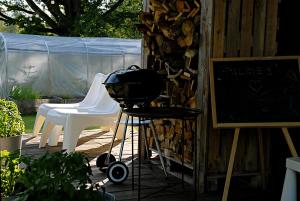 a grill and two white chairs on a patio at Pelēkā Māja, forestside getaway house for cosy stays in Myza Brenguli